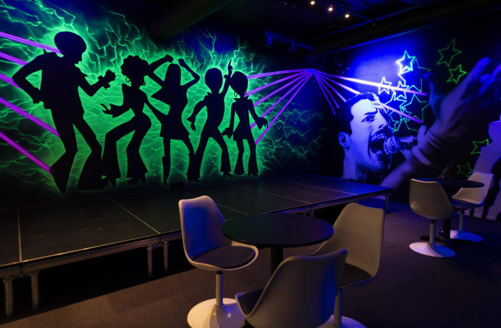 Neon-lit karaoke room with stage and colorful wall art