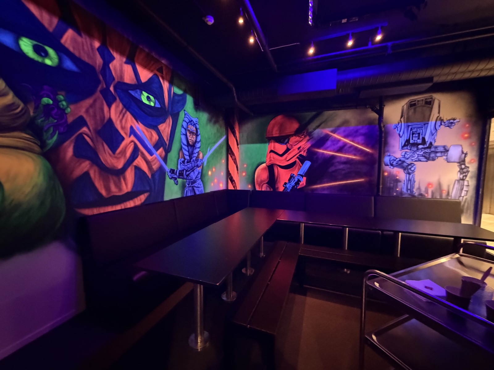 Blacklight-Geburtstagszimmer mit farbenfrohen Wandmalereien und Sitzplätzen